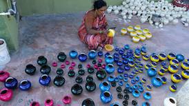 Indisk kunstner lager fargerike potter