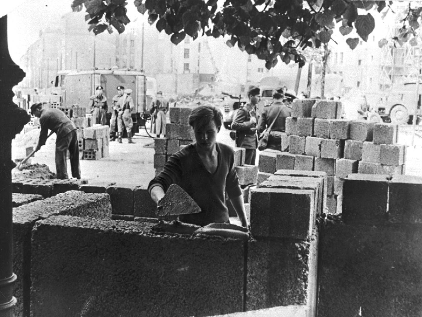 Bildet er fra de første delene av Berlinmuren ble bygd 13. august 1961. En person smører mørtel på betongblokken for å gjøre klar for neste høyde med mur. Foto: Peter Hillebrecht / AP / NTB