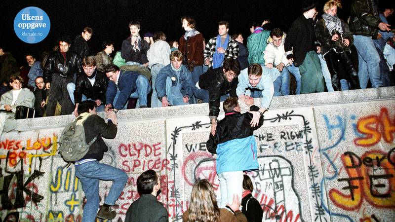 Bildet viser folk oppå Berlinuren. Noen hjelper andre med å klatre opp.
