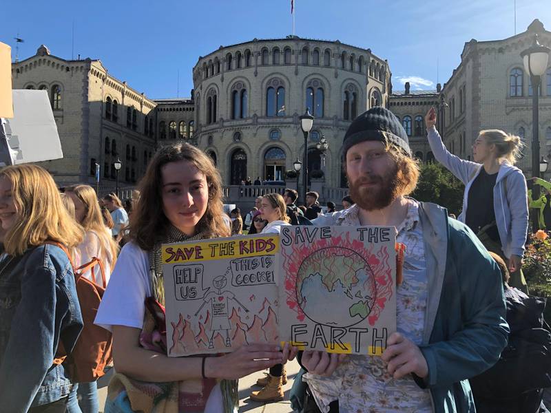 Bildet viser Giselle Penny og Luke Petersen fra Australia. De står foran Stortinget med plakater. De var med og demonstrerte for klimaet i Oslo. 