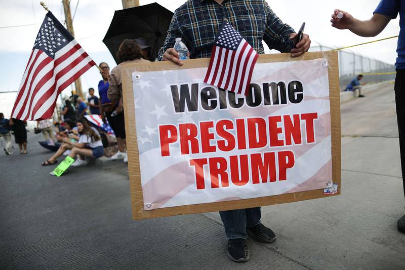 Bildet viser en mann som holder en plakat til støtte for Trump i El Paso.