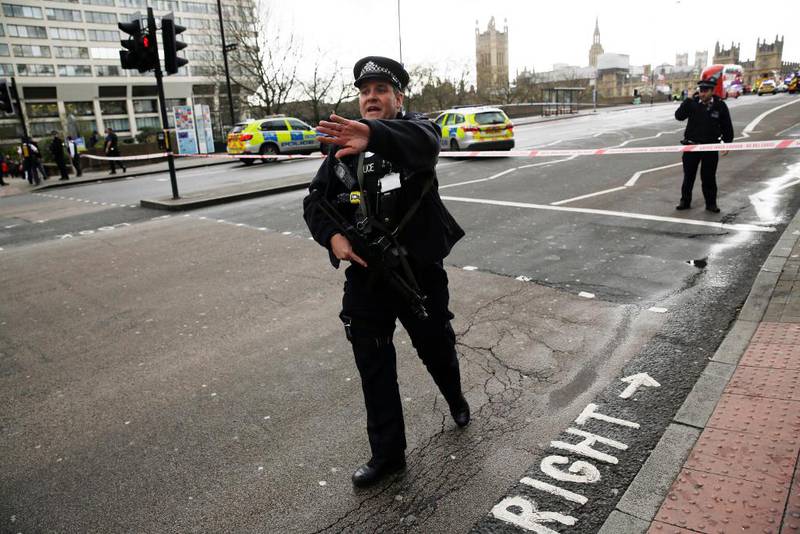 Bildet viser en politimann i London som ber folk gå bort. 