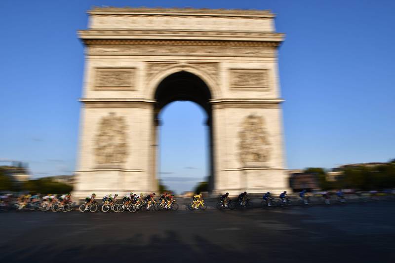 Bildet viser flere syklister som kjører forbi Triumfbuen i Paris i Frankrike.