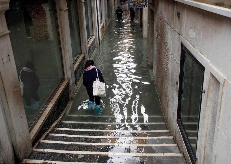 People wade their way through water in Venice, Italy, Friday, Nov. 15, 2019. Waters are rising in Venice where the tide is reaching exceptional levels just three days after the Italian lagoon city experienced its worst flooding in more than 50 years. (AP Photo/Luca Bruno)