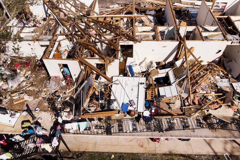 Bildet viser en mann i restene av et hus. Mange andre hus området er ødelagt.