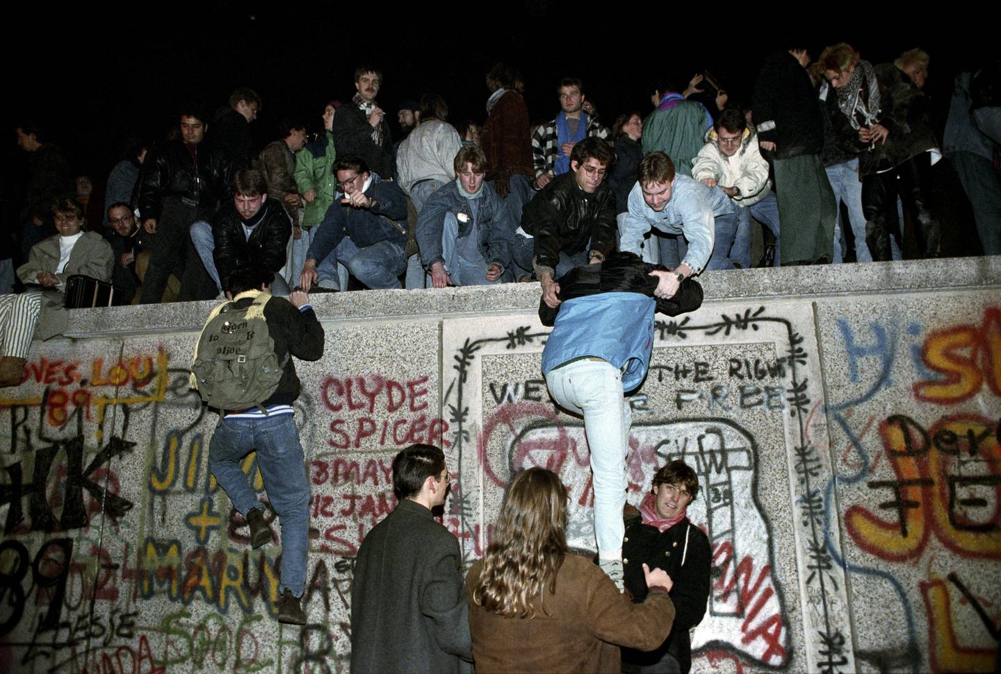 Bildet er av folk som klatret opp på Berlinmuren i november 1989. Foto: Jørn H. Moen / NTB