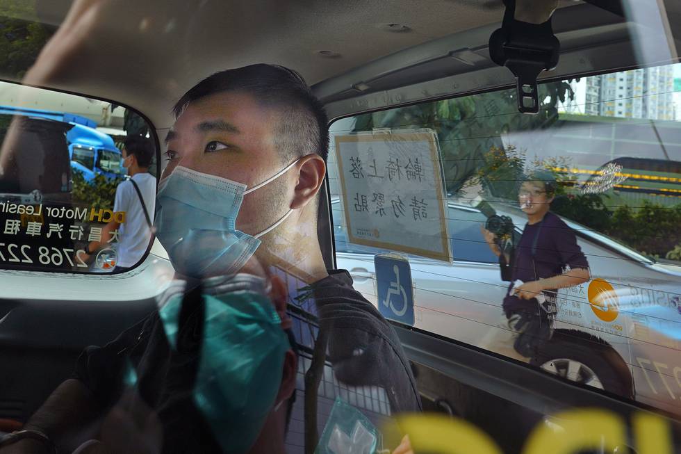 Bildet er av Tong Ying-kit. Han sitter med munnbind i baksetet på en bil.. Foto: Vincent Yu / AP / NTB