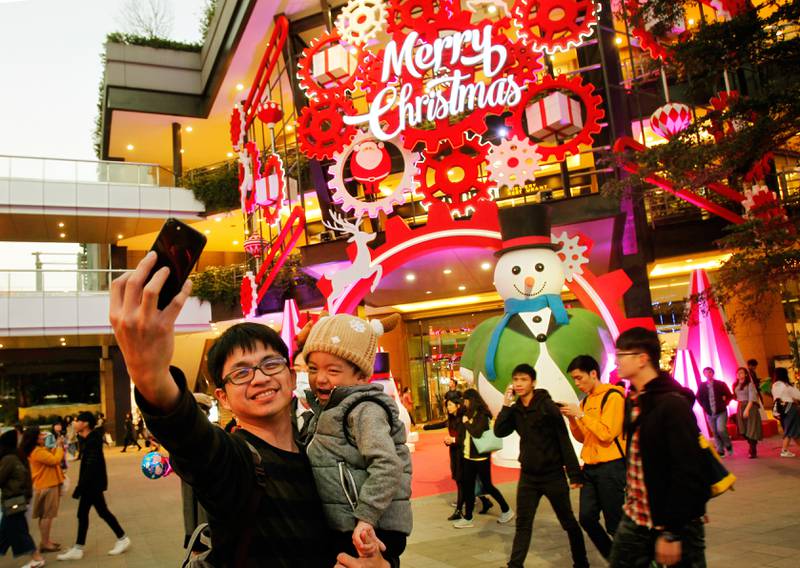 Bildet viser en far og en sønn som tar en selfie foran julepynten i Taipei i Taiwan.
