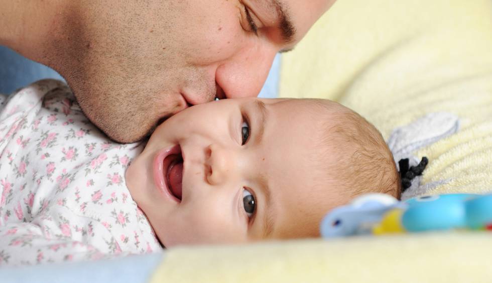 Bildet viser en pappa som kysser en baby.