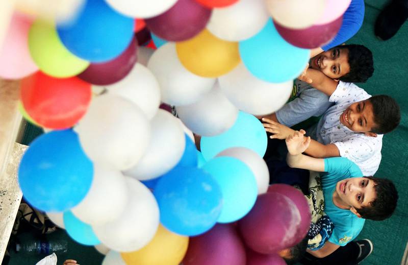 Bildet viser barn som strekker seg etter ballonger.