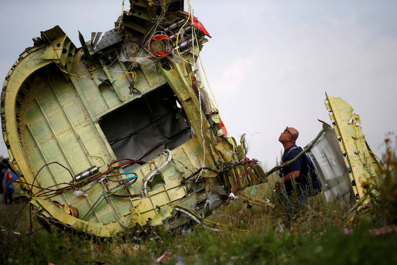 Bildet viser en mann som ser på en del fra det styrtede flyet.