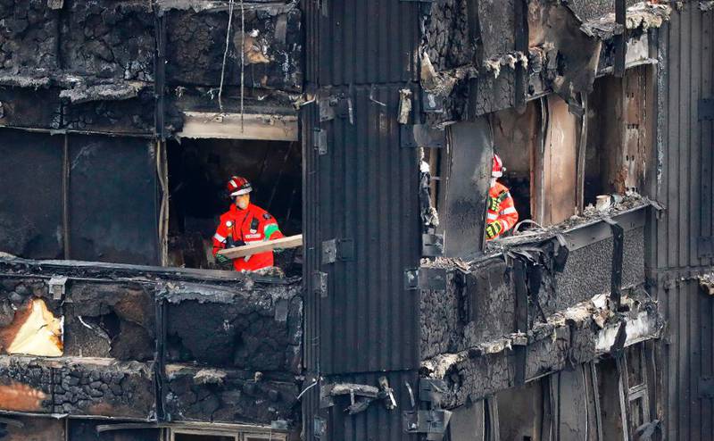 Bildet viser en brent bygning. I ett av vinduene står en brannmann.