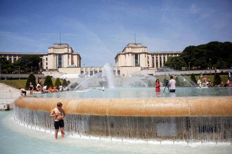 Bildet viser folk som kjøler seg ned i en fontene i Paris.