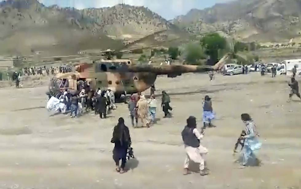 Bildet er av folk som står rundt et helikopter. Det skal frakte folk bort fra jordskjelvområdet.