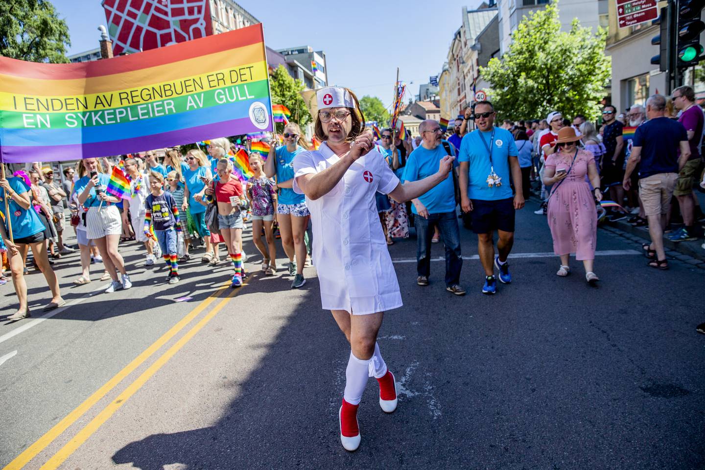 En person går i Pride-paraden. Hen har på seg sykepleieruniform.