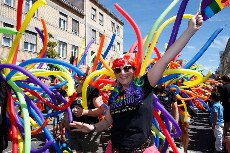 Bildet viser glade mennesker med fargerike ballonger under Oslo Pride.
