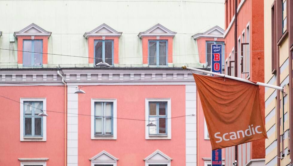 Bildet er av et rødt flagg med logoen til hotellkjeden Scandic på. I bakgrunnen er det en annen bygård. Foto: Geir Olsen / NTB