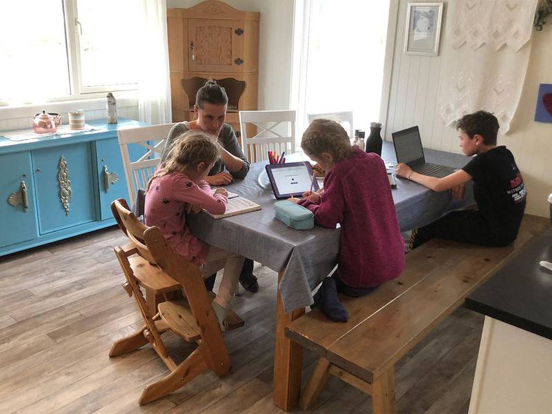 Bildet viser Marit Kvinlaug og de tre barna. De sitter rundt et bord og har hjemmeskole. Det er vanskelig å følge opp tre barn, sier Kvinlaug. Fire av fem i familien har dysleksi. 