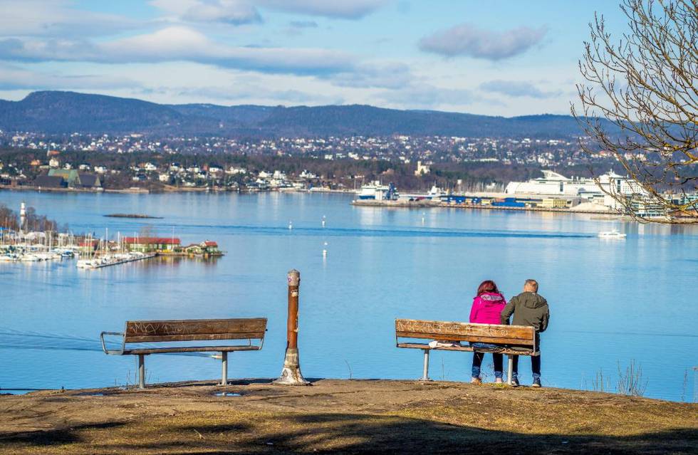 Bildet er av et par som sitter på en benk og ser utover vannet. Utsikten er fra Ekeberg i Oslo. Det er småbåthavn til venstre i bildet. Byen og havna for ferjene til Danmark og Tyskland er i bakgrunnen.