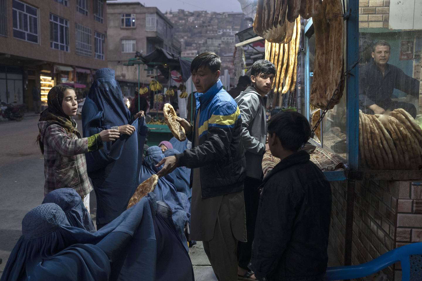 En mann deler ut brød til afghanske kvinner utenfor et bakeri i Kabul torsdag denne uken. Etter 20 år med vestlig militært nærvær gjenerobret Taliban makten i landet tidligere i år. Foto: Petros Giannakouris / AP / NTB