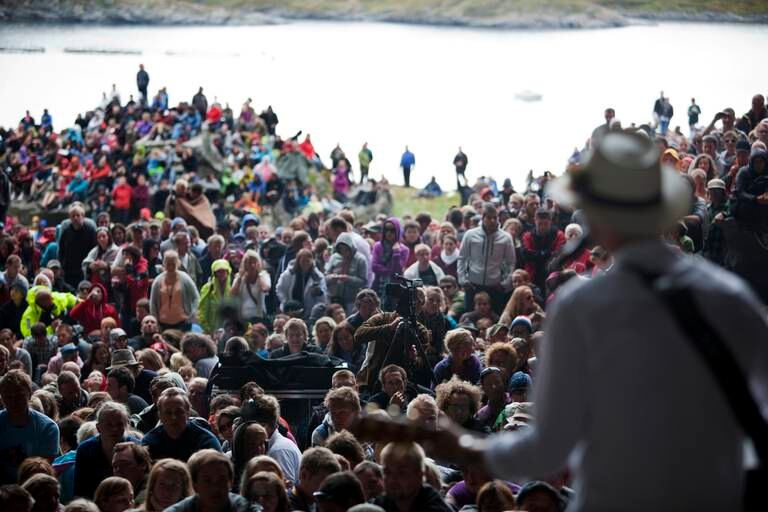 Bildet er av folk som står og ser på en konsert. Det er mulig å se sjøen bak dem. Bildet er fra Træna. Foto: Tore Meek / NTB