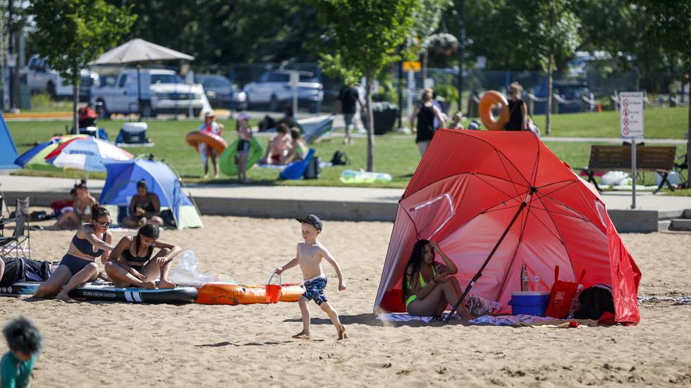I Canada søker folk seg til stranden for å holde ut varmen. Her fra Chestermere. Foto: Jeff McIntosh / The Canadian Press via AP / NTB
