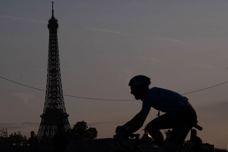 Bildet viser svarte omriss av en syklist foran Eiffeltårnet.