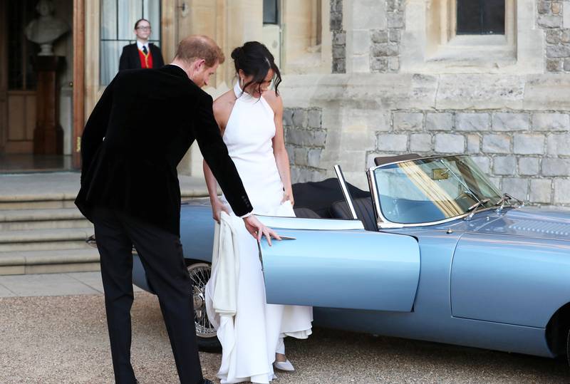Bildet viser hertuginne Meghan og prins Harry som reiser til bryllupsfesten i en blå sportsbil.