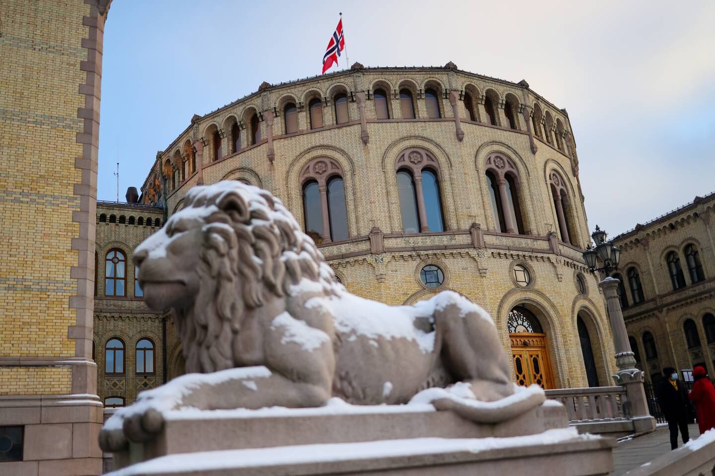 Bildet viser Stortinget med en løvestatue dekket av snø foran.
