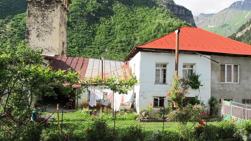 Bildet viser et hvit hus i landsbyen Ieli i Svaneti. Huset har en fin hage. Her vokser det røde roser.