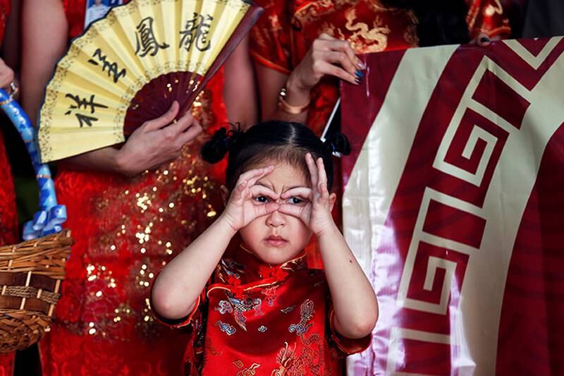 Thailand: Ei jente har på seg en tradisjonell, kinesisk kjole. Hun ønsker velkommen kinesiske turister. Seremonien skjer på flyplassen i Bangkok i Thailand. 