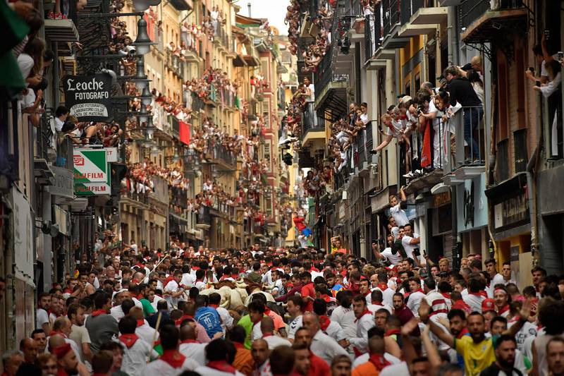 Bildet viser folk på balkonger som ser på at okser og mennsker løper gjennom gatene i Pamplona.