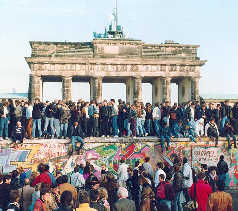 Bildet viser mange mennesker oppå Berlinmuren foran Brandenburger Tor 10. november 1989.