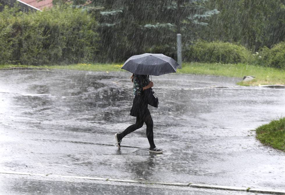 Bildet viser en kvinne som løper i regnet med en paraply. Fra mandag ettermiddag til tirsdag morgen er det fare for både styrtregn, lyn og torden på Østlandet.