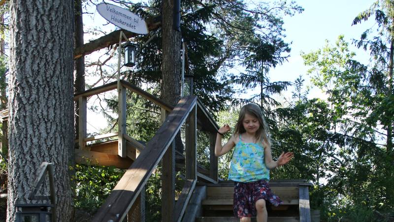 Bildet viser en jente som går ned trappene til tretopphytta.