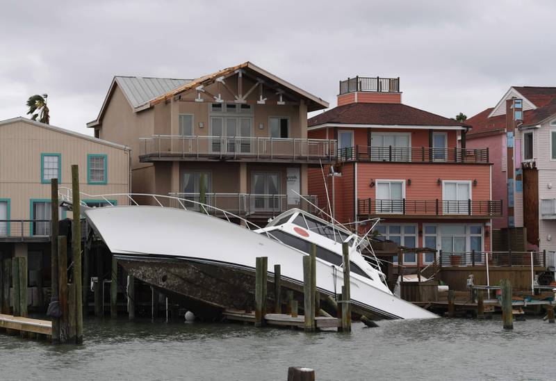 Bildet viser en båt som ligger inntil noen hus ved vannet.