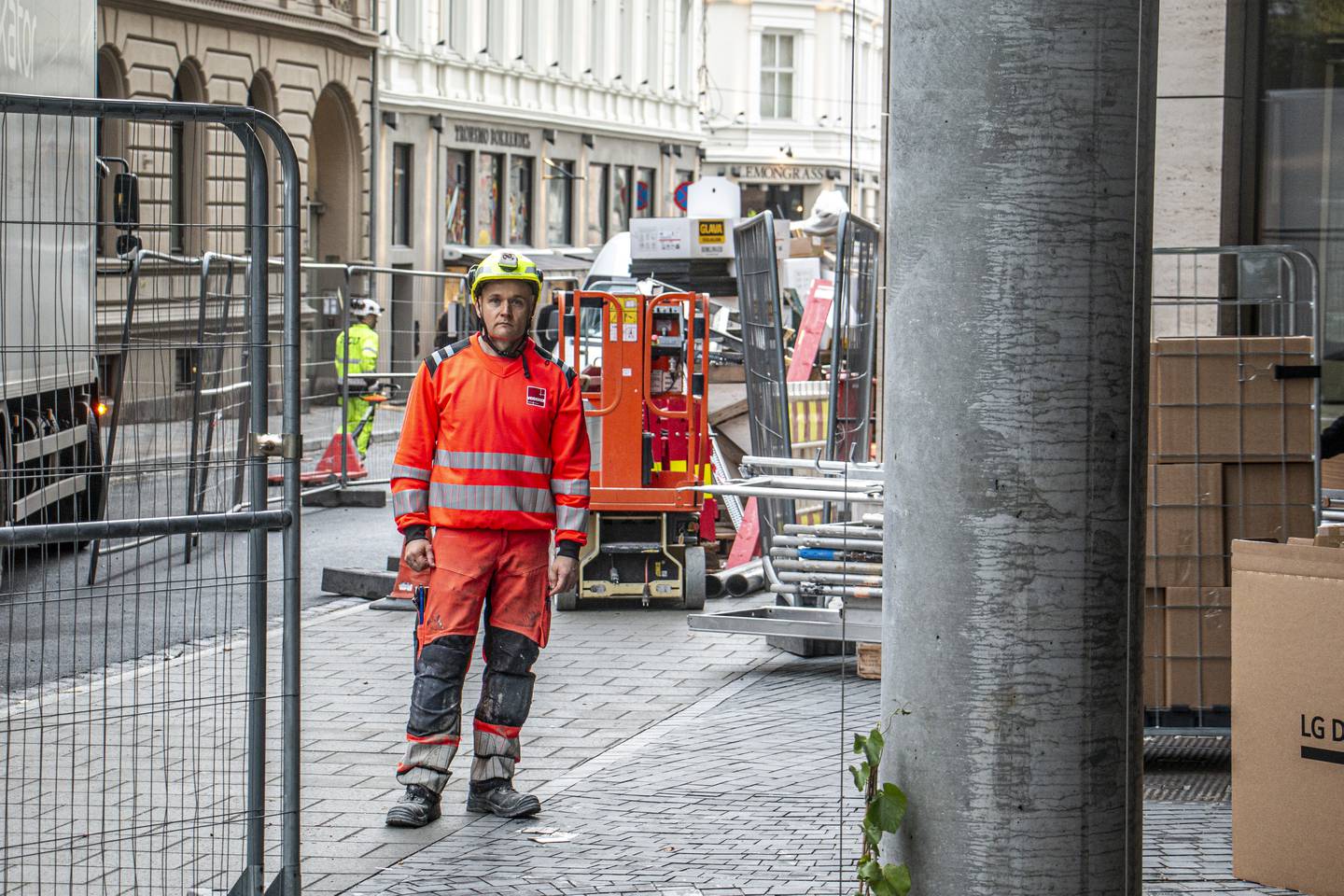 Bildet er av en mann i reflekterende arbeidsantrekk. Han har på hjelm, og er omgitt av maskiner og gjerder i en gate i Oslo.