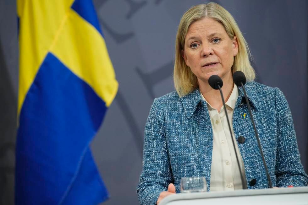 Bildet er av den svenske statsministeren Magdalena Andersson.Hun står bak en mikrofon, ved siden av et svensk flagg. Det er blått, med et gult, horisontalt kors. Foto: Martin Sylvest / Ritzau Scanpix / AP / NTB
