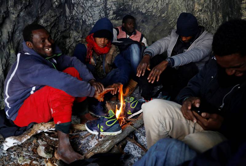Bildet viser migranter rundt et båk i en hule.