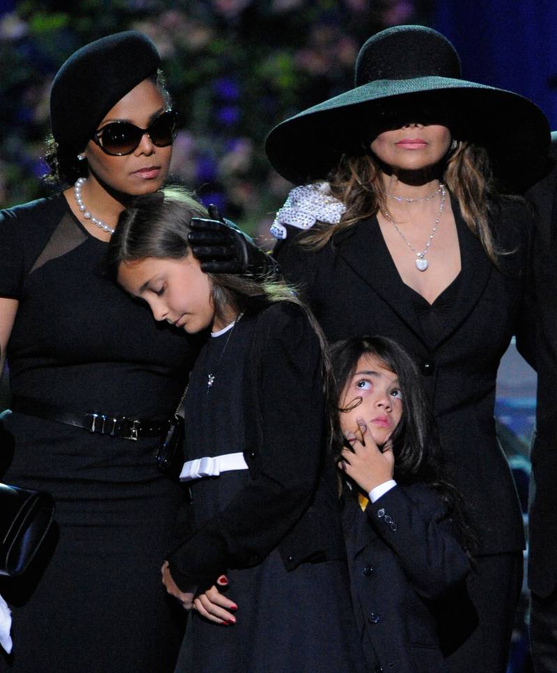 Bildet er fra minnestunden til Michael Jackson. Det viser Jacksons søstre som holder rundt to av barna til Jackson.