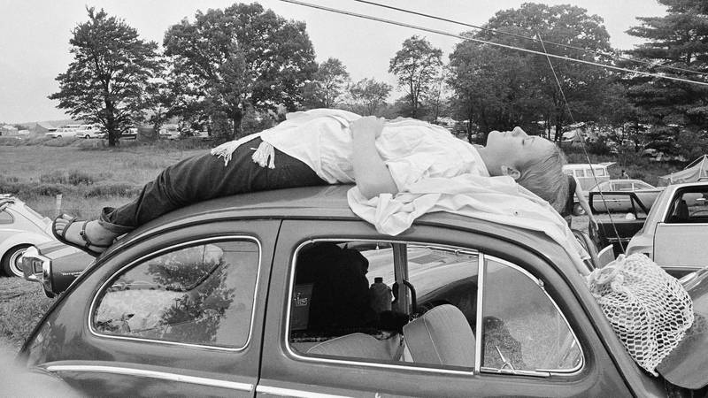 Bildet viser en kvinne som sover på taket av en bil.