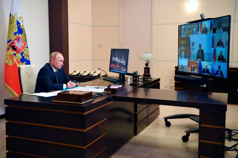 Bildet er av Vladimir Putin. Han sitter bak en pult. Han deltar på en videokonferanse. Foran pulten er en stor skjerm med de andre deltakerne.