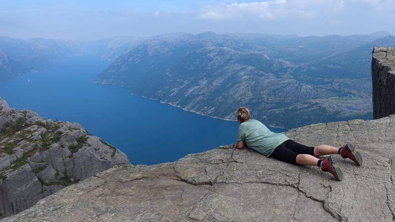 Bildet viser en turist som ser utover Lysefjorden fra Preikestolen.