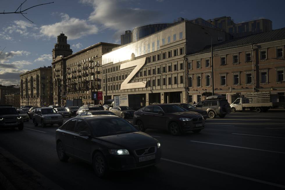 Bildet er fra Moskva. Det viser biler som kjører i en travel gate. I bakgrunnen er et stort bygg. Det er en tre etasjer høy utgave av bokstaven Z på fronten av bygget. Foto: AP / NTB