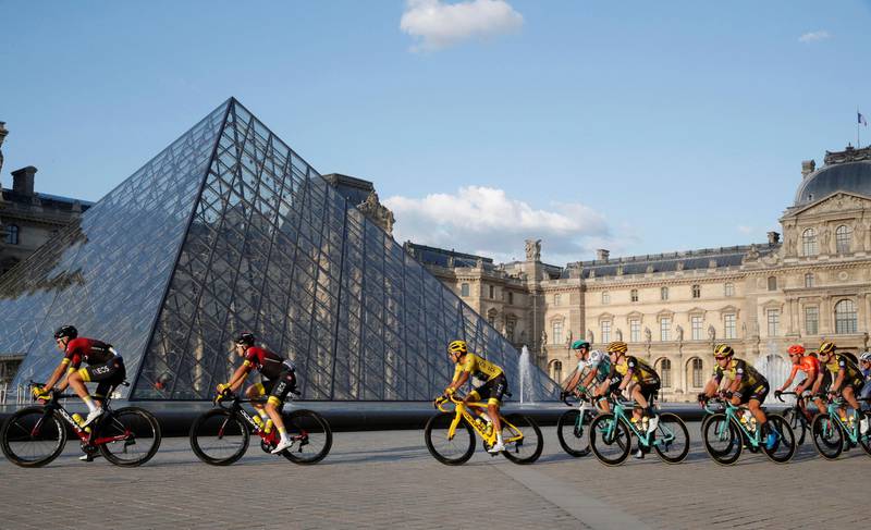 Bildet viser syklister som kjører foran glasspyramiden over plassen foran museet Louvre.