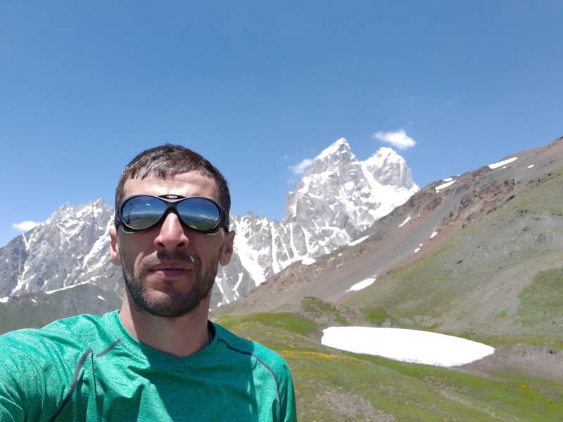 Bildet viser Lasha Tkeshelashvili. Han er guide i fjellene i regionen Svaneti. I bakgrunnen ser du fjellet Ushguli.