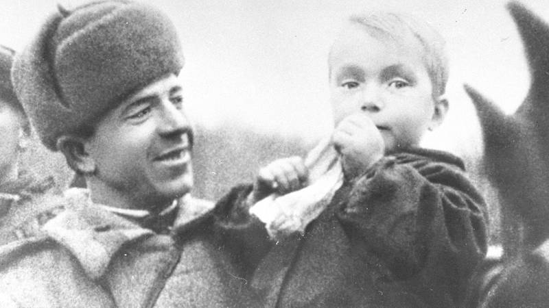 Bildet viser en sovjetisk soldat som holder en norsk gutt.