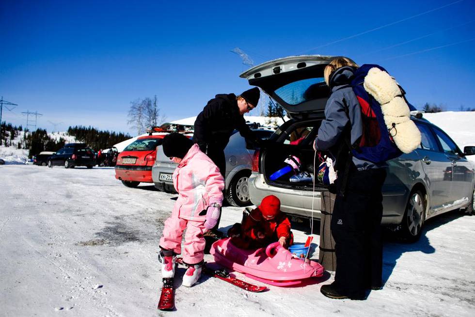 Bildet viser en familie som pakker ut av bilen. De tar på seg ski. 