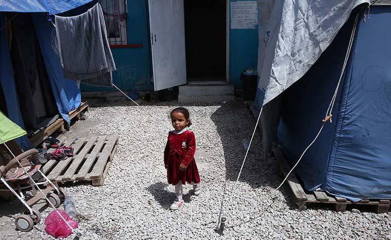 Bildet viser en liten jente som står mellom teltene i leiren. Hun er i den delen av leiren hvor myndighetene skal finne ut hvem migrantene er. 
