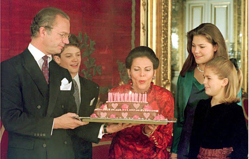 Bildet viser dronning Silvia som blåser ut lysene på en kake. Familien er samlet rundt henne.